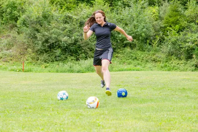 Eine junge Fußballgolf-Spielerin beim Abschlag auf dem Rasen